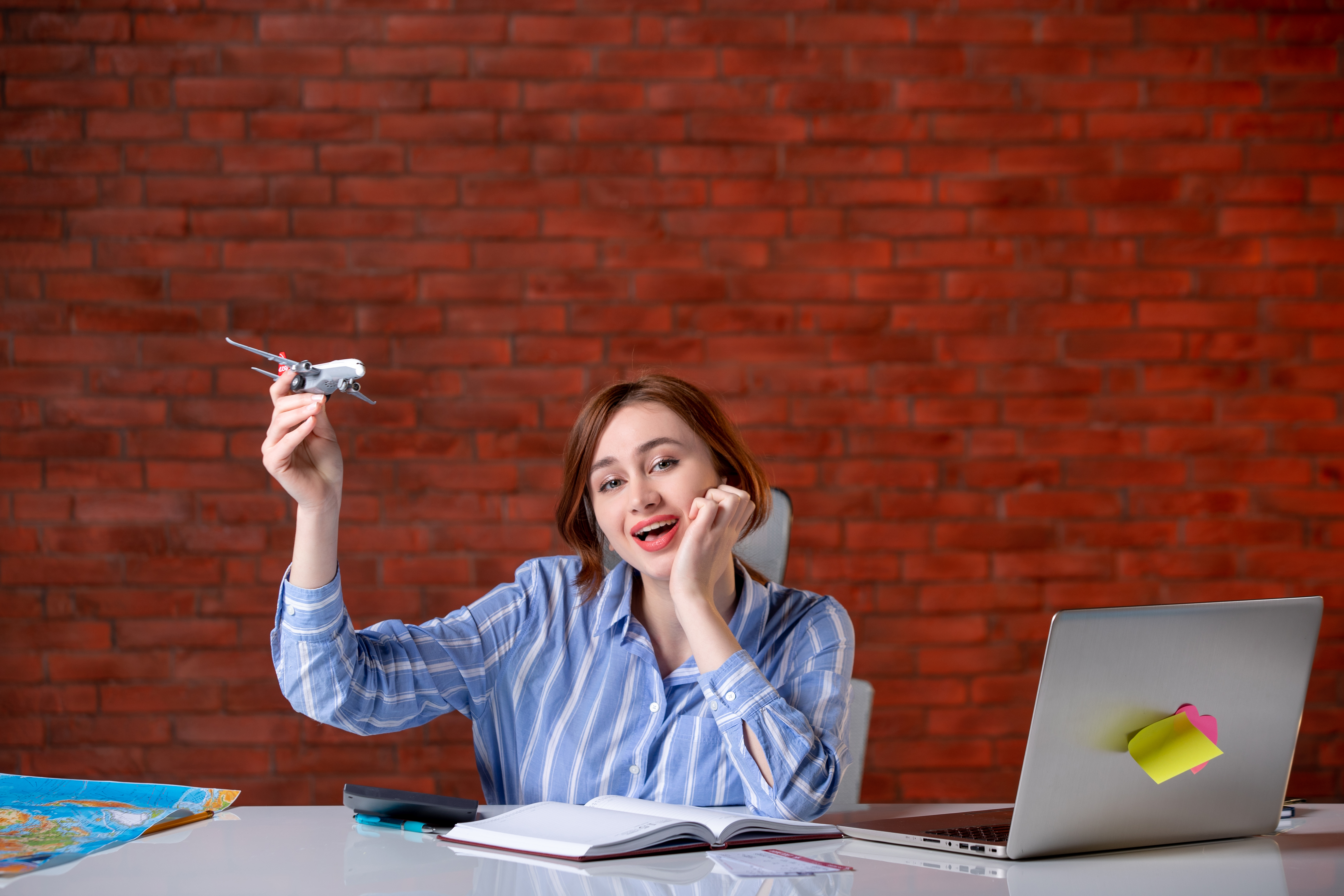 front-view-travel-agent-sitting-her-working-place-playing-with-toy-plane-agency-service-assistant-ticket-manager-map-operator-world